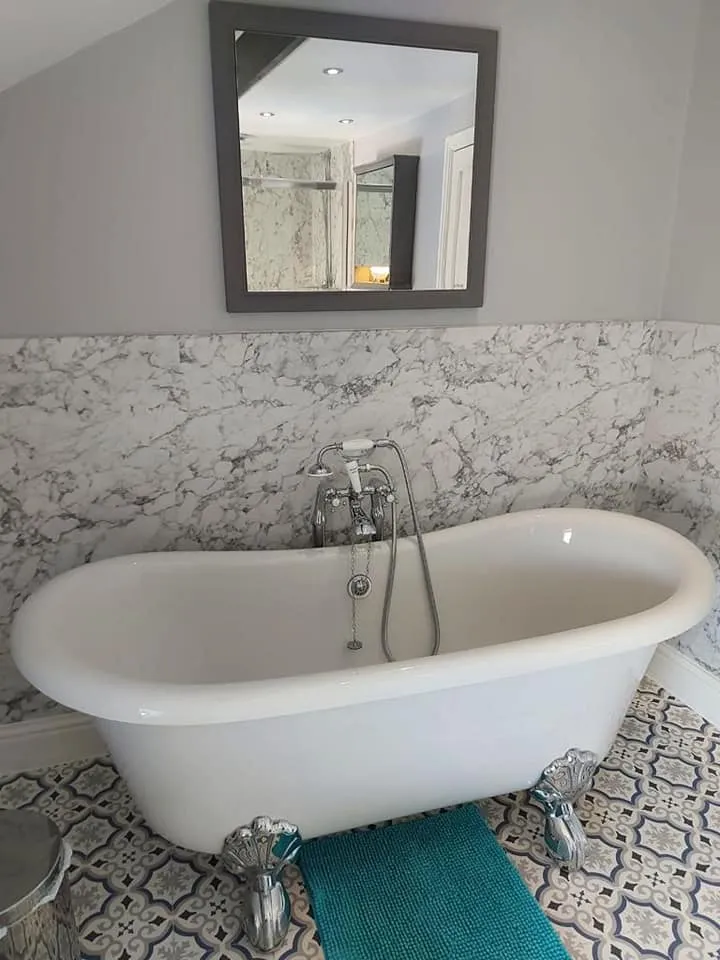 A white bath tub sitting under a bathroom mirror.
